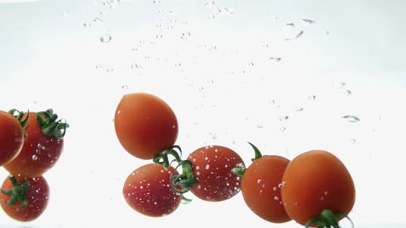 Closeup of Fresh and Health Cherry Tomatoes Falling Into Clear Water with Big Splash on White