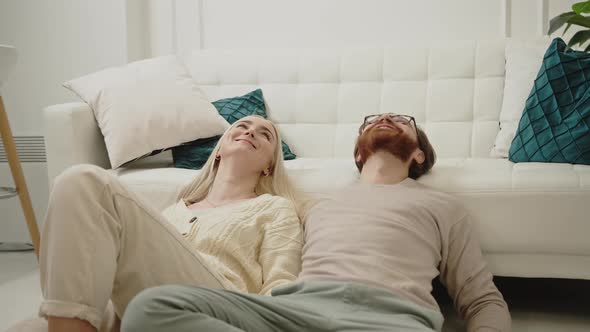 Content Caucasian Couple Celebrating Women's Day Laying on the Floor Looking Up and Smiling