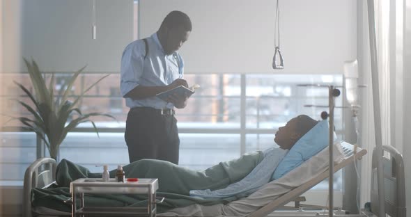 Afroamerican Detective Interrogating Woman Victim Lying in Hospital Bed