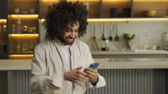 Muslim Man Plays Game and Wins in Smartphone in Kitchen