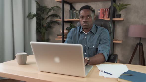 African Man Employee Works in the Office at the Computer. Black Businessman Looking at Laptop Screen