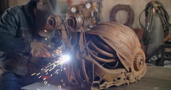 Locksmith Welds the Decorative Metal Steampunk Snail Sculpture with a Lot of Sparks and Flashes in