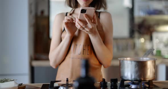 Woman Using Phone While Cooking