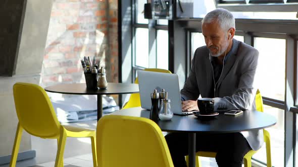 Businessman having coffee while using laptop in hotel