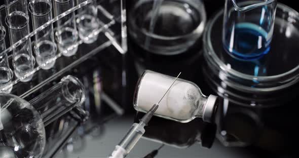 Laboratory Equipement: Syringe and Medicine, Test Tubes and Flasks Rotating on Black Background