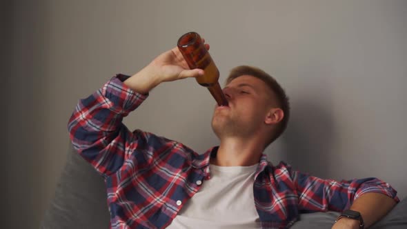 A Young Man Drinking Beer While Sitting on the Couch