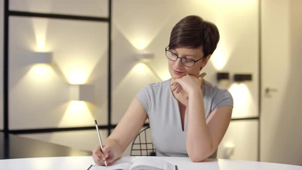 Woman Writing Business Ideas in Notepad