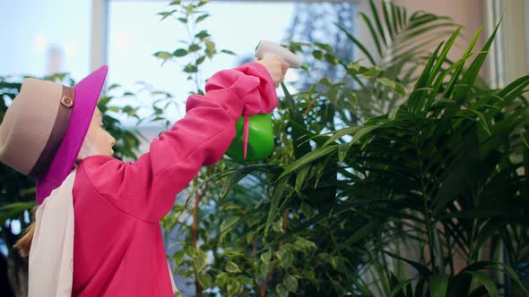 Cute Elegant Girl Spraying Green Plants Indoors