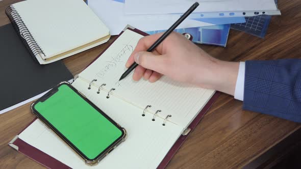 Man Using Smart Phone in Office Space Sitting on Chair and Using Green Screen Phone Mockup Chroma