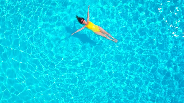 View From the Top As a Woman in a Yellow Swimsuit Lying on Her Back in the Pool