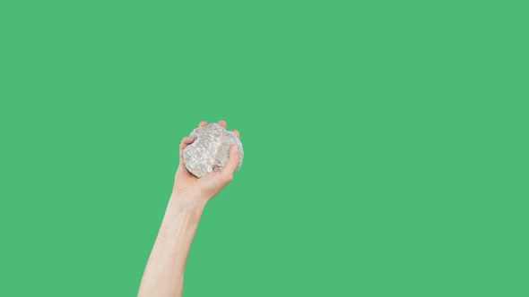 Human Hand Holding Cobblestone on Green Chromakey Background. Raised Hand with Stone on Green Screen