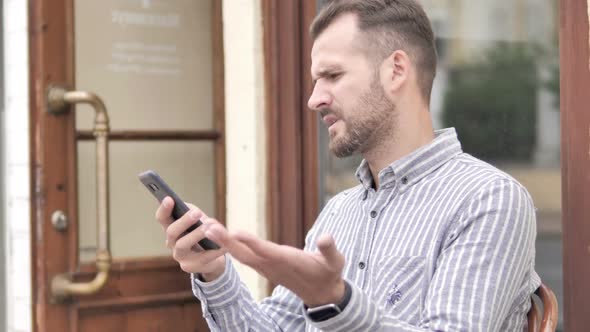 Man Upset By Loss While Using Smartphone