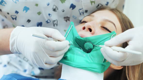 A doctor in white gloves treats a girl teeth to a patient