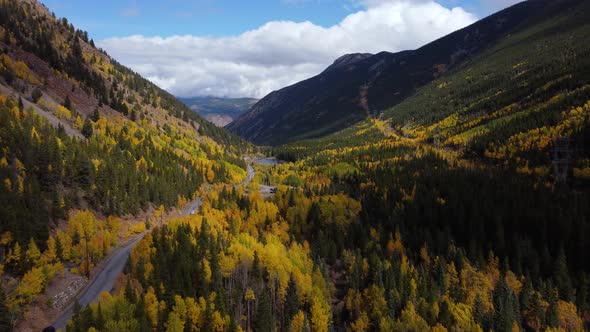 Flying over golden aspens along road through mountain pass in Colorado, Aerial