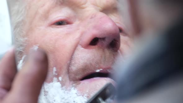 Old Grayhaired Older Grandfather Applying Foam to Face for Shaving and Looking in the Mirror