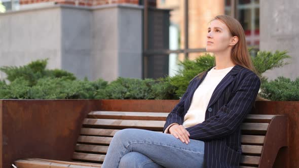 Young Business Woman Sitting Outside Office and Looking Around