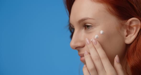 Portrait of Pretty Woman Applying Cream on Her Face