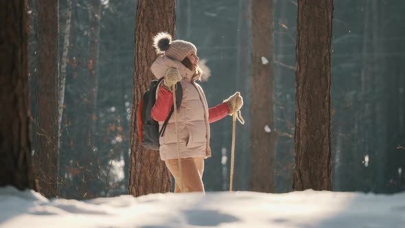 Young Woman Skier Looks with Admiration at the Snowy Forest