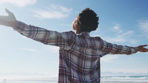 African american woman with arms wide at the beach on sunny day