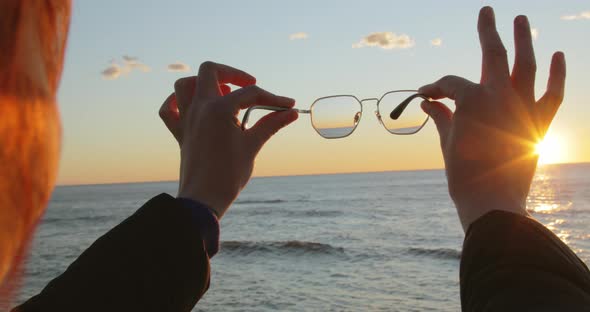 Looking to the Future Concept with Eyeglasses Held By a Girl at Sunrise Ocean