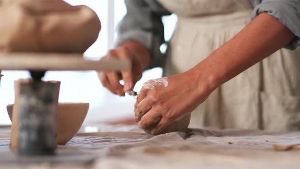 Woman potter cutting bowl of clay