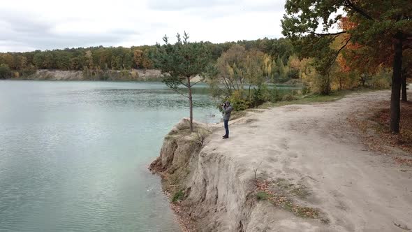 Man standing on shore. Aerial view of man standing on lake shore and taking photo of nature