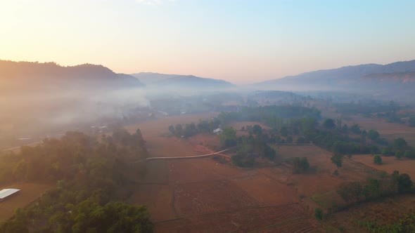 Aerial view over villages and barren fields in countryside during sunrise