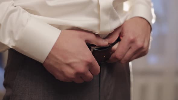 Groom Wears Belt Man in White Shirt Puts Belt on Pants in Wedding Morning Businessman Preparation