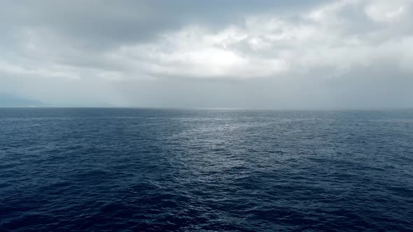 Camera flies over the open dark ocean  and loneliness boat to rainy clouds 
