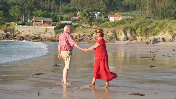 Anonymous senior couple standing on beach by waving sea