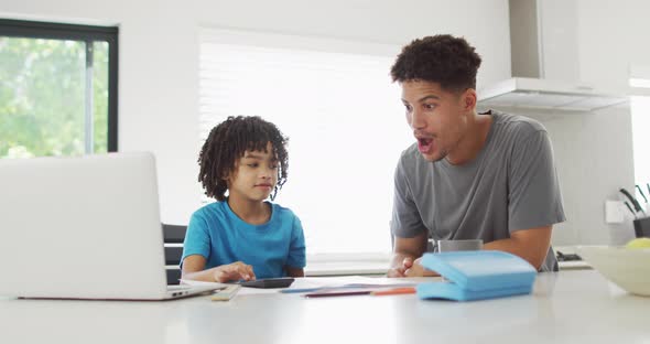 Happy biracial man and his son doing homework together, highfiving