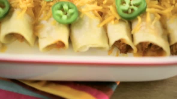 Chicken enchiladas with cheddar cheese and sauce.
