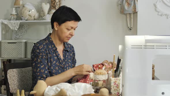 Middle aged woman sewing a doll alt