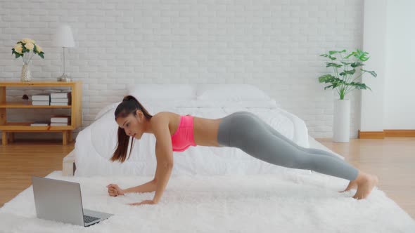 Athletic Healthy Asian woman in sportswear workout excercise online course at home