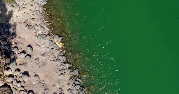 Rocky Beach and Green Lake Water on a Sunny Day