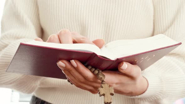 Close Up of a Woman Holding Bible Book and Wooden Beads