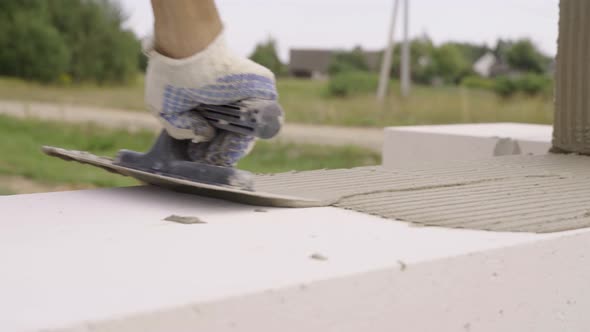 builder applies adhesive composition or solution with spatula to put next block.