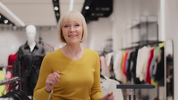 Cheerful Active Mature Professional Female Saleswoman Dancing in Clothing Store Advertises New