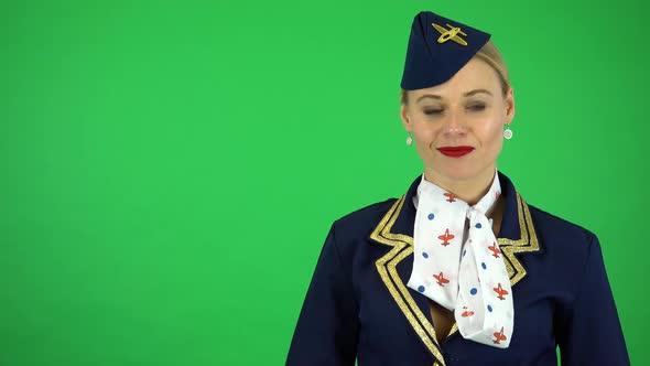 A Young Beautiful Stewardess Nods and Smiles at the Camera - Green Screen Studio