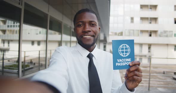 Pov Shot of Afroamerican Businessman Talking on Camera Holding Vaccine Passport