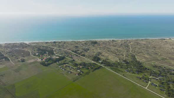 Panoramic view, north sea, summer houses built on grassy sand dunes, green meadows