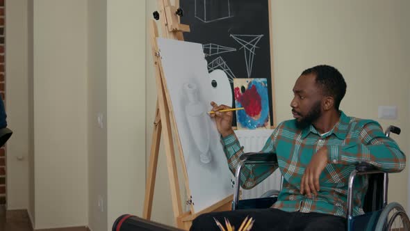 African American Man with Disability Using Pencil to Draw on Canvas