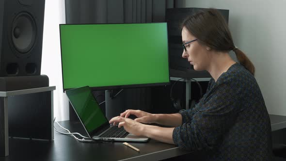 Female employee working on laptop computer from home workplace green screen.