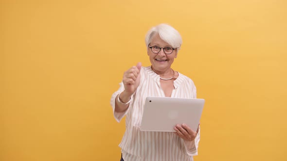 Excited Senior Lady Showing Thumbs Up After Looking at Laptop Screen