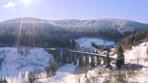 Train crossing a stone railway viaduct,left to right,winter landscape.