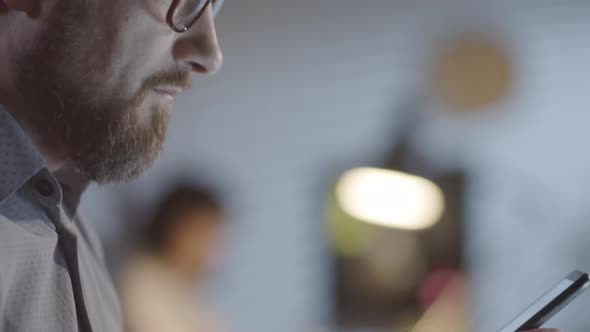 Cheerful Man Texting on Phone in Dark Office