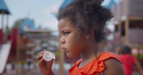 Close Up of African Preschool Child Blowing Soap Bubbles on Sunny Day in Playground