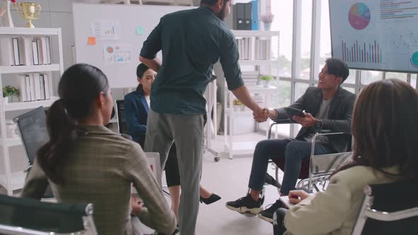 Confident businessman in wheelchair shaking hands with colleague in meeting room.