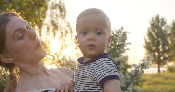 Lovely Mother Kisses Toddler While She Holds Him on Hands and Has Joy in Park