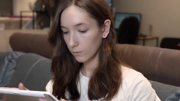 A Young Girl Uses a Tablet at Home